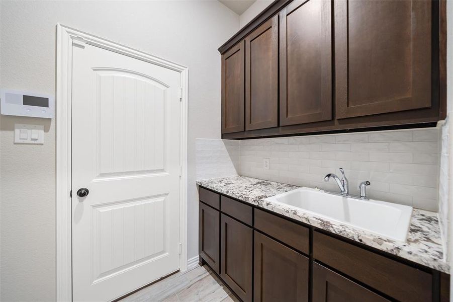 Laundry room featuring a sink and light wood-style floors Laundry room featuring a sink and light wood-style floors