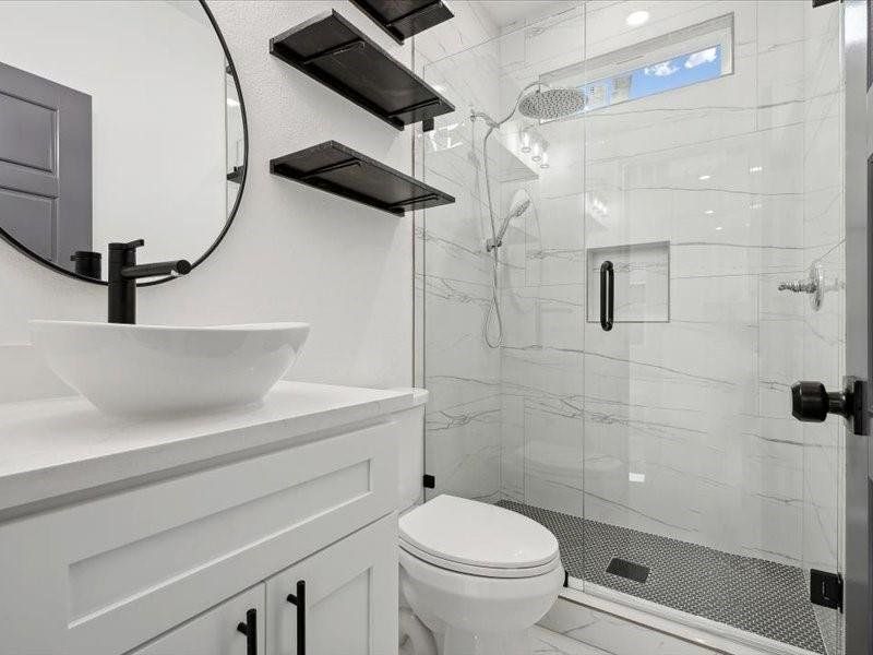 Bathroom featuring vanity, toilet, tile patterned floors, and walk in shower