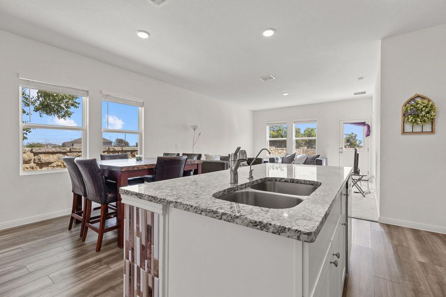 Kitchen featuring a kitchen island with sink, light stone counters, white cabinets, and recessed lighting Kitchen featuring a kitchen island with sink, light stone counters, white cabinets, and recessed lighting