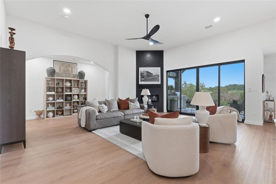 Spacious living area featuring light wood-finish flooring and a contemporary ceiling fan