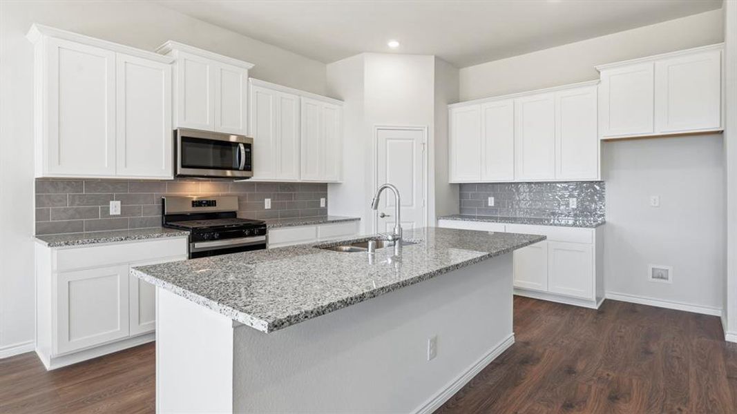 Kitchen featuring backsplash, stainless steel appliances, white cabinets, light stone countertops, and dark wood finished floors Kitchen featuring backsplash, stainless steel appliances, white cabinets, light stone countertops, and dark wood finished floors