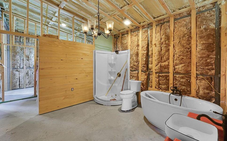 Miscellaneous room featuring unfinished concrete floors, wood walls, and a chandelier Miscellaneous room featuring unfinished concrete floors, wood walls, and a chandelier