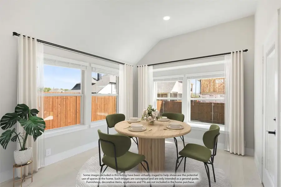 Bright dining area with round wood table, green chairs, vaulted ceiling, and large windows with white curtains