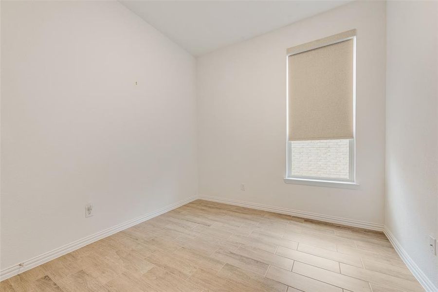 Spare room featuring light wood-style floors and lofted ceiling Spare room featuring light wood-style floors and lofted ceiling