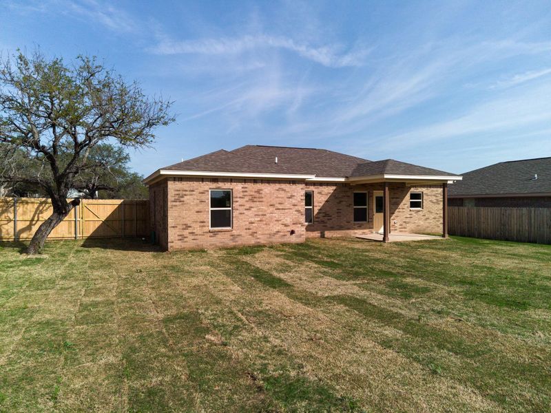 Rear view of property with a lawn, a fenced backyard, a patio, brick siding, and roof with shingles Rear view of property with a lawn, a fenced backyard, a patio, brick siding, and roof with shingles
