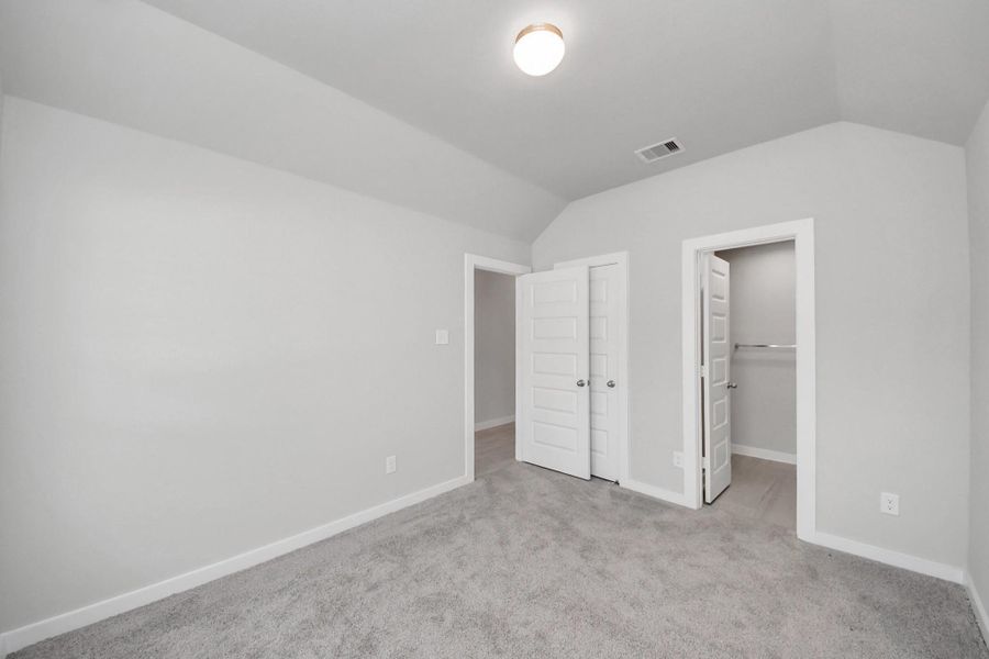 Spacious fourth bedroom featuring a walk-in closet and a private ensuite bathroom. Door to the left leads to the entry hallway, providing convenient access while maintaining privacy for guests or family members.