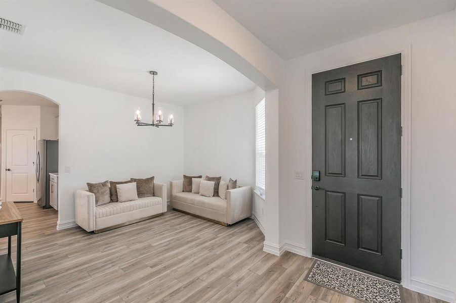 Entrance foyer featuring light hardwood / wood-style floors and an inviting chandelier