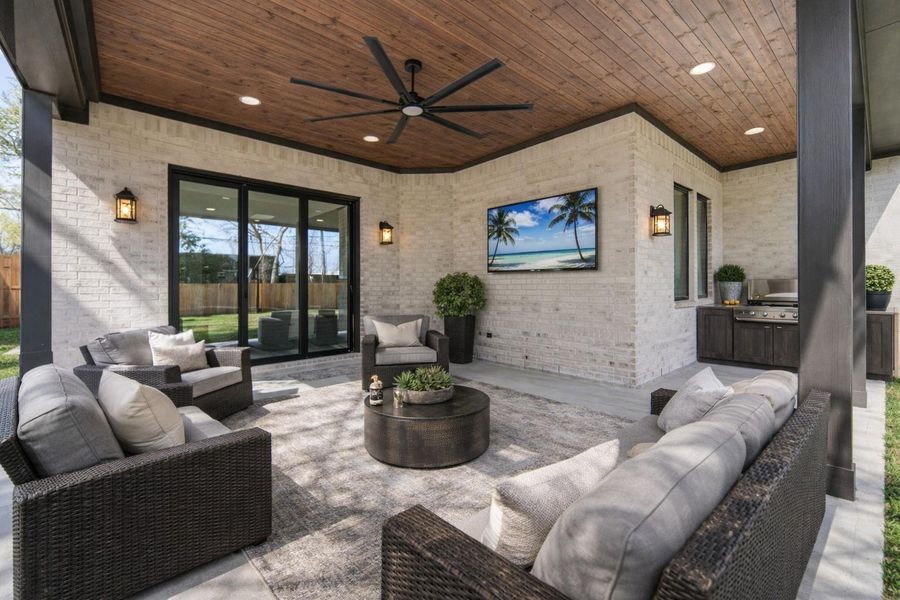 Stunning outside covered area that is preplumbed for an outdoor kitchen. *This home is virutally staged and the outdoor kitchen show is for ideas