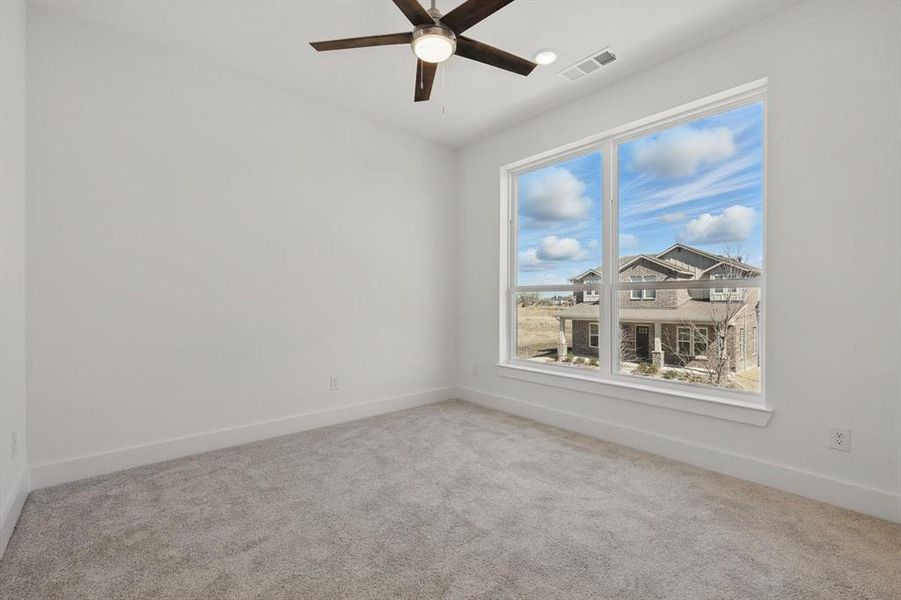 Carpeted spare room featuring baseboards, visible vents, and a ceiling fan