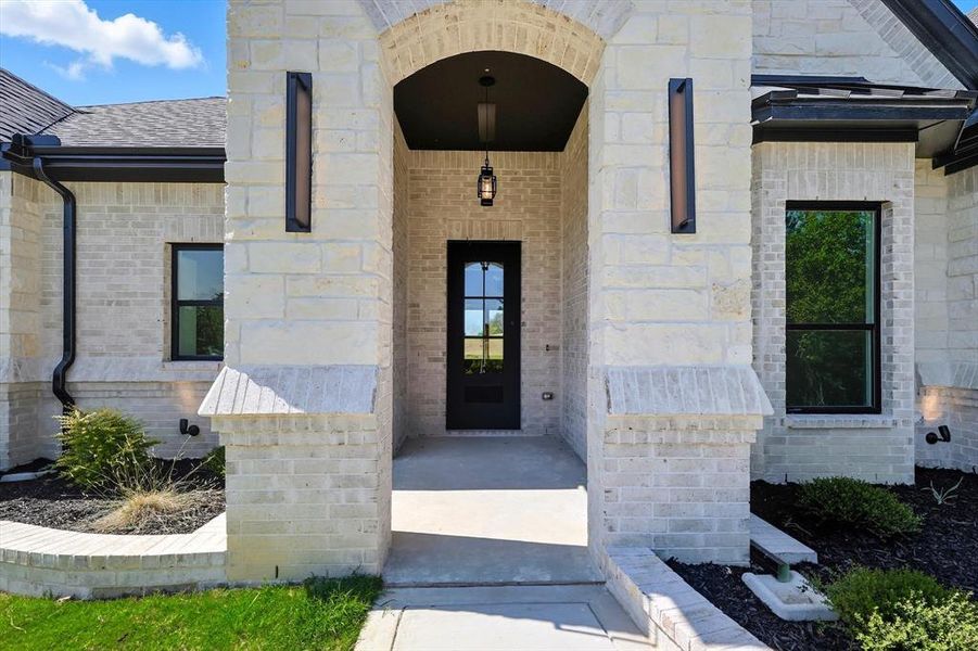 Entrance to property featuring stone siding and brick siding