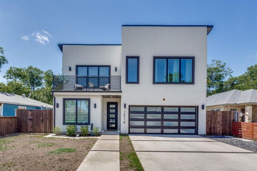 Modern home featuring a balcony, an attached garage, stucco siding, and concrete driveway