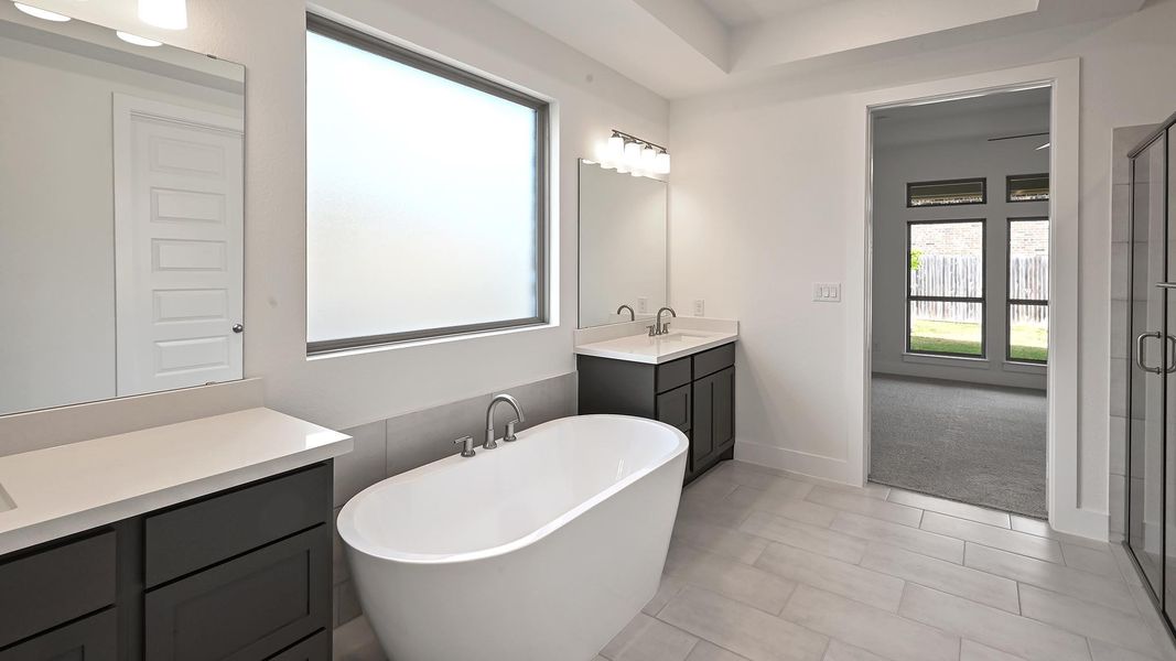 Bathroom with a freestanding tub, two vanities, plenty of natural light, and light tile patterned floors Bathroom with a freestanding tub, two vanities, plenty of natural light, and light tile patterned floors