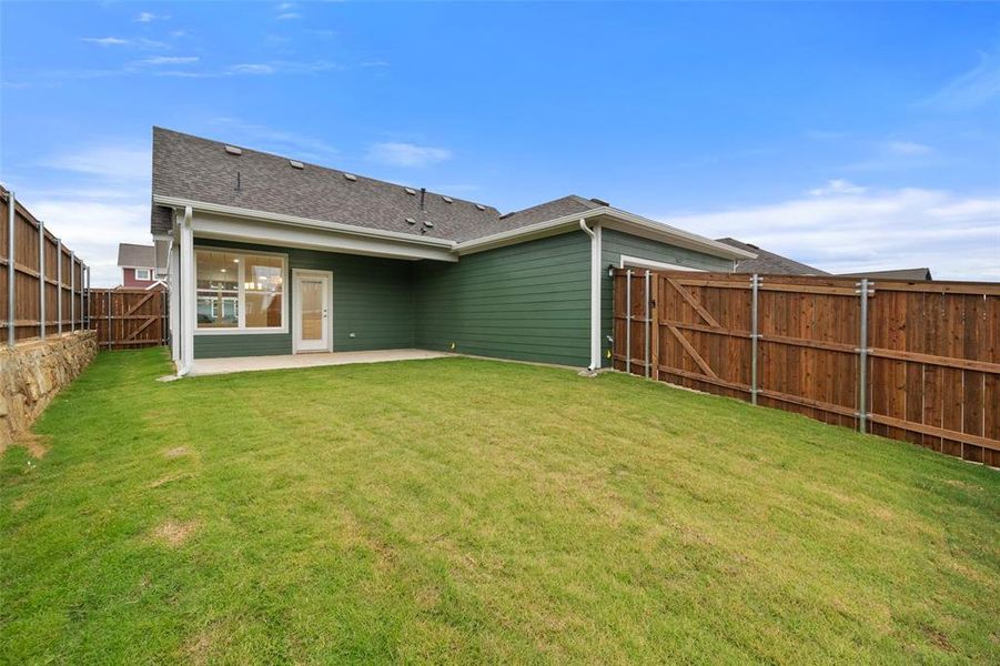 Back of house with a lawn and a patio