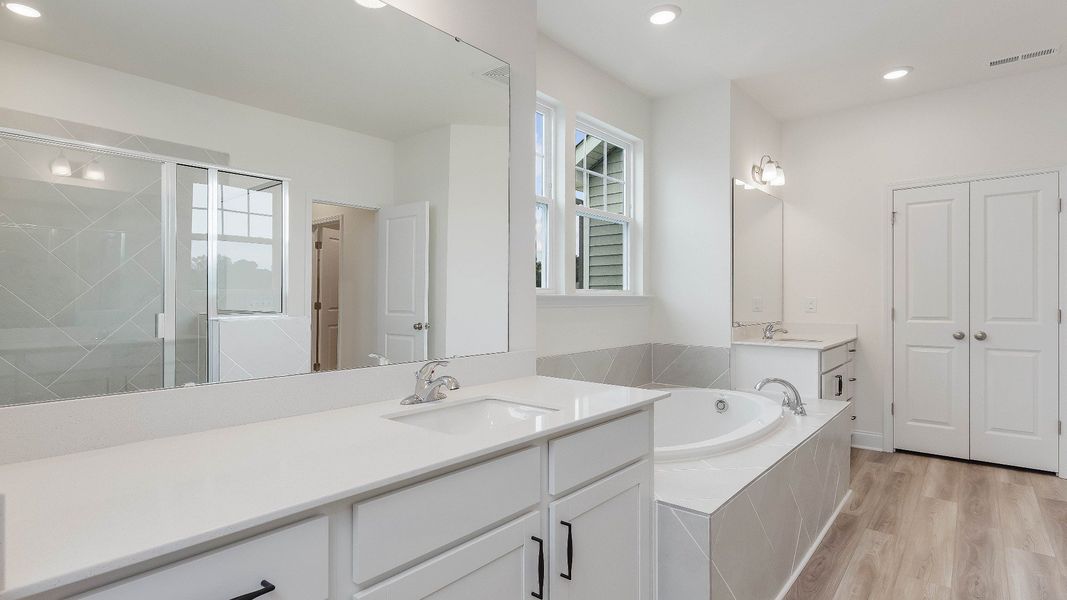 Stonehaven home plan primary bathroom with separate vanities, soaking tub, linen closet and tile shower Stonehaven home plan primary bathroom with separate vanities, soaking tub, linen closet and tile shower