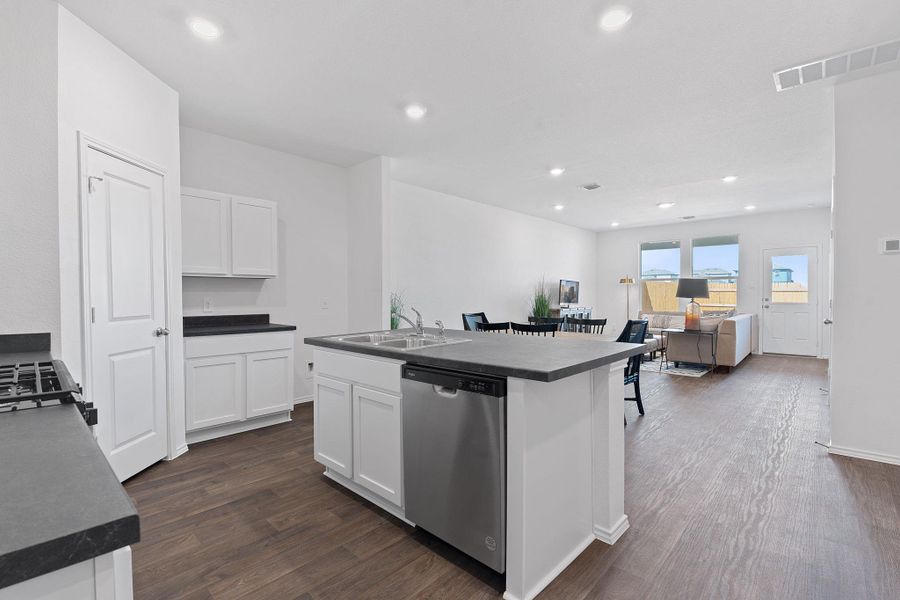 Kitchen with a sink, dark countertops, visible vents, and dishwasher