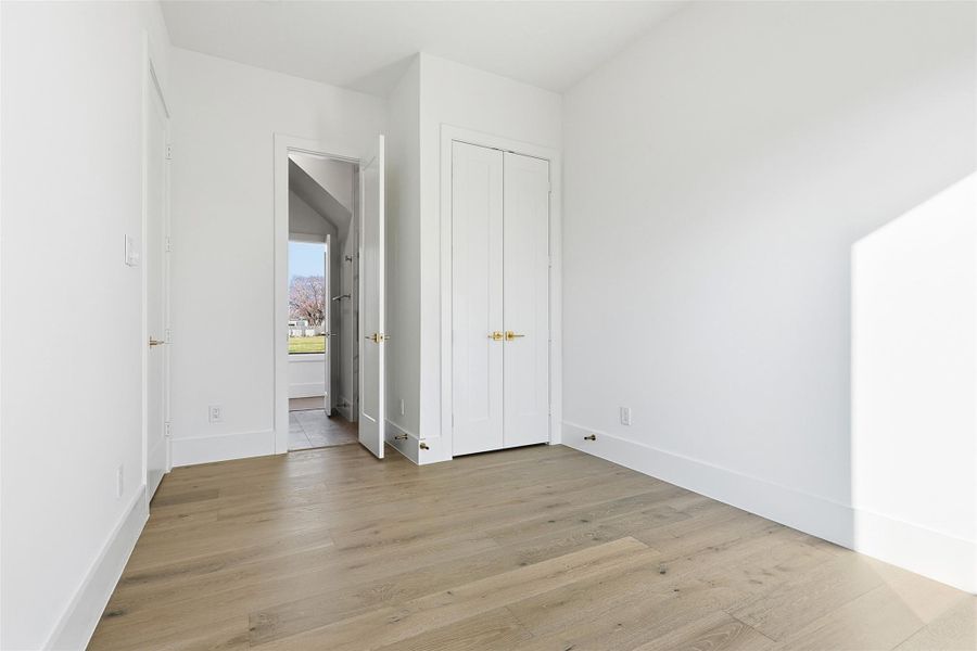 Same floorplan - different finishes. This versatile bedroom space includes light wood floors, minimalist white walls, and double-door closet storage.