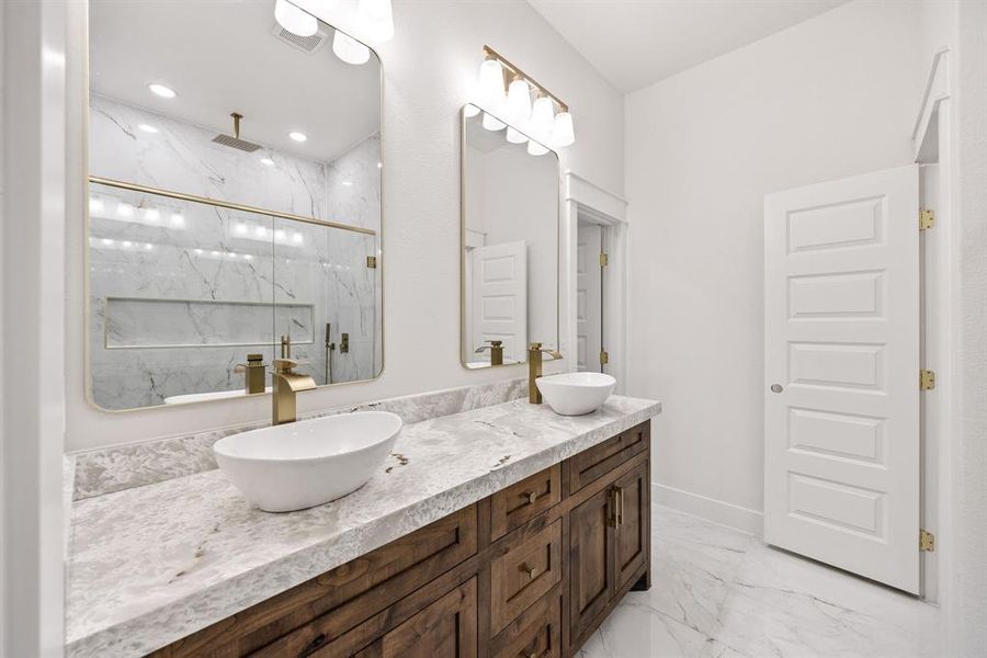 Bathroom featuring light marble finish flooring, a marble finish shower, double vanity, and recessed lighting