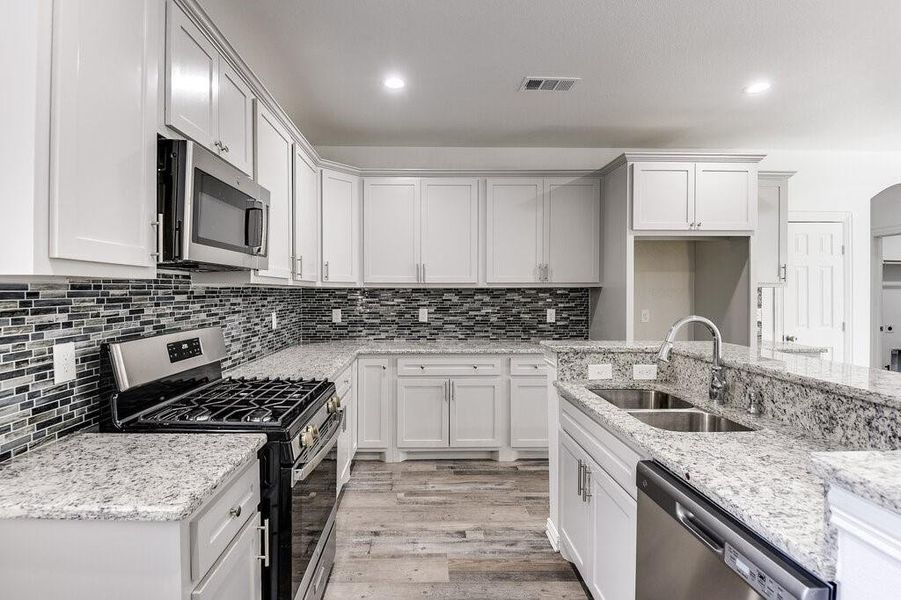 Kitchen with white cabinetry, light hardwood / wood-style flooring, appliances with stainless steel finishes, and sink