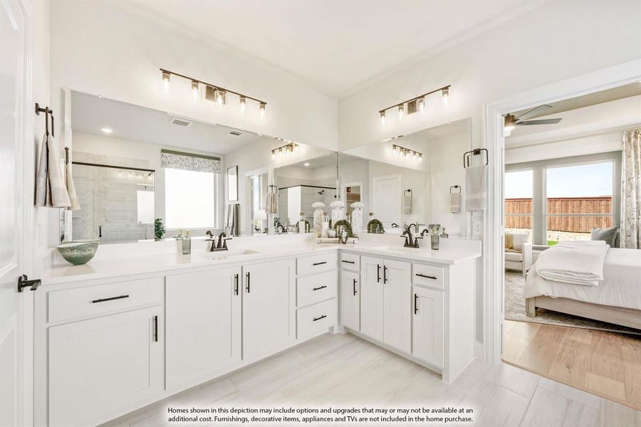 Master bathroom with dual vanity, white cabinets, and large mirrors, open to bedroom with hardwood floors