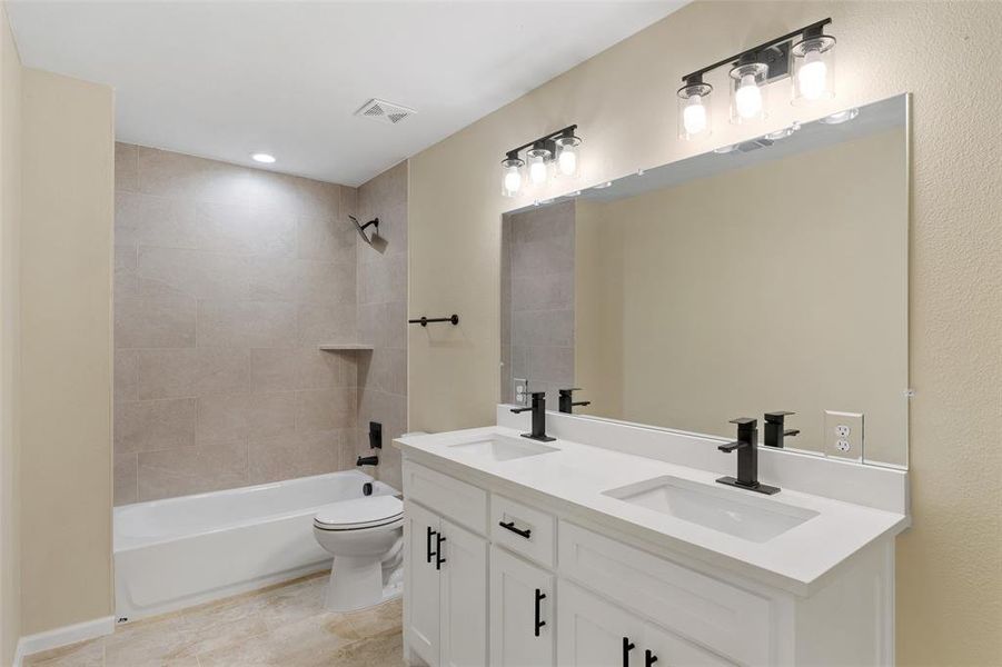 Full bathroom with tile patterned floors, vanity, toilet, and tiled shower / bath