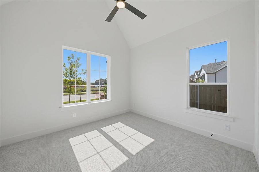 Carpeted spare room with high vaulted ceiling and ceiling fan Carpeted spare room with high vaulted ceiling and ceiling fan