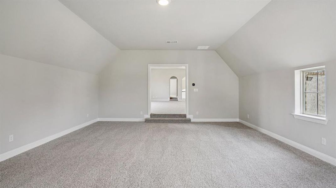 Additional living space featuring lofted ceiling and light carpet Additional living space featuring lofted ceiling and light carpet