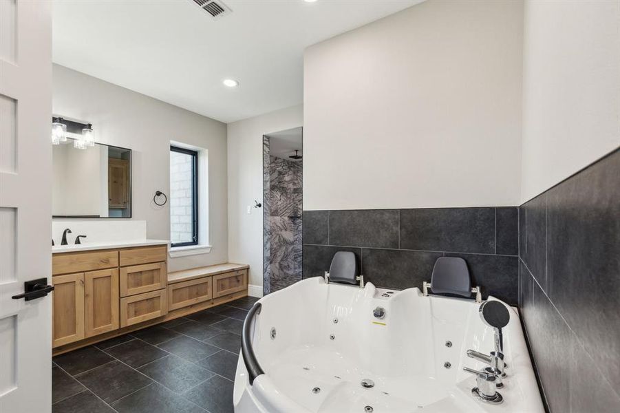 Primary bathroom with jetted tub for 2, double sink vanity, and recessed/decorative lighting. Primary bathroom with jetted tub for 2, double sink vanity, and recessed/decorative lighting.