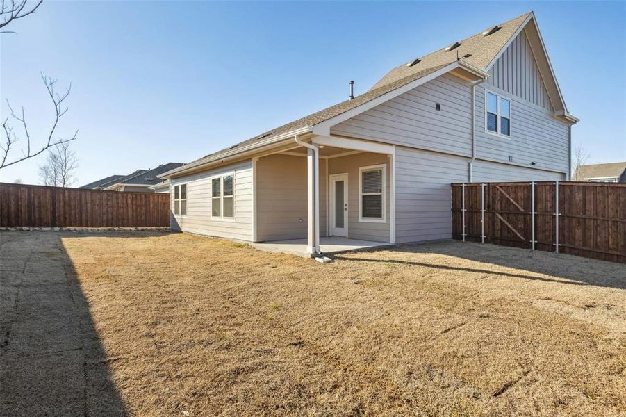 Spacious backyard with a covered patio, privacy fencing, and a two-story exterior featuring siding and gabled rooflines