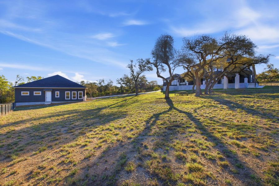 The property includes a spacious, grassy yard with mature trees, providing natural shade