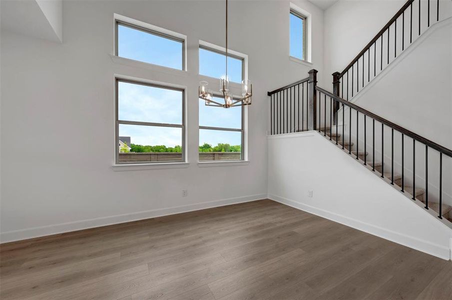 This bright interior features high ceilings, a contemporary chandelier, and large windows that provide abundant natural light