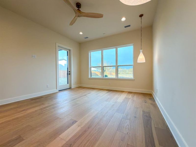 Spacious room featuring wood-finish flooring, a wall of windows, a glass-paneled exterior door, a contemporary ceiling fan, and recessed lighting