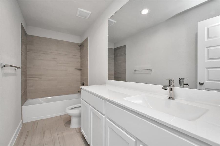 Bath/shower combo surrounded by tasteful tile in this secondary bath. Sample photo of completed home with similar plan. As built color and selections may vary.