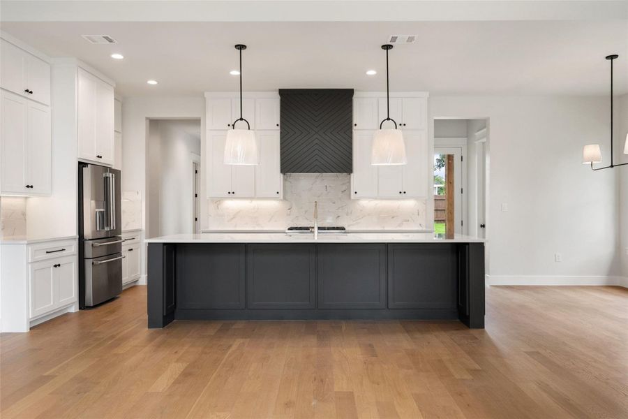 Culinary dreams come alive in this kitchen featuring a striking dark island and gleaming stainless steel appliances.