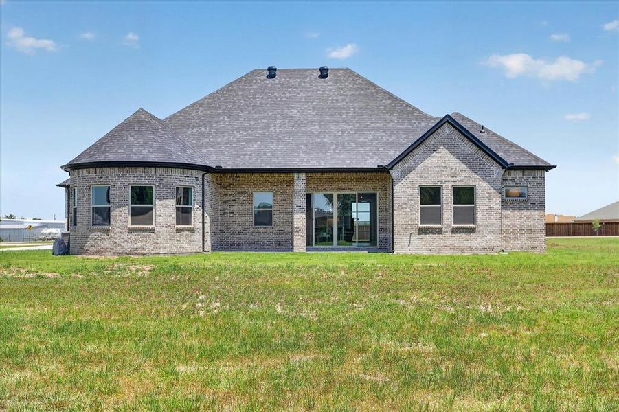 Rear exterior showcasing a brick facade, multiple window placements, and a covered patio area with sliding glass doors