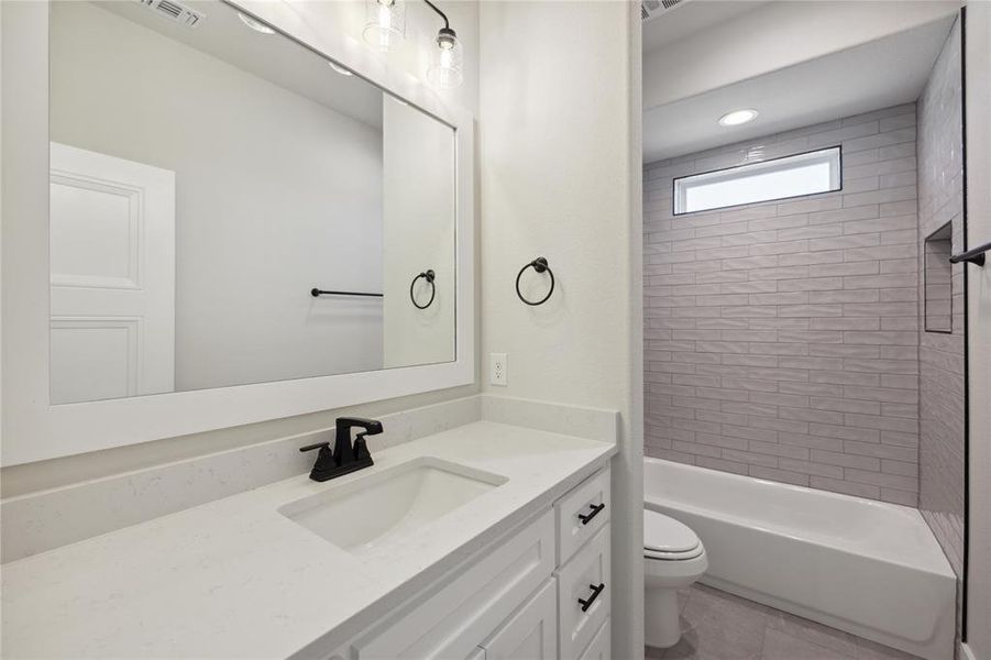 Full bathroom featuring tiled shower / bath, vanity, toilet, and tile patterned floors