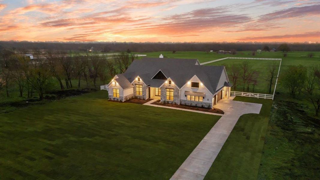 View of front of home with stone siding, driveway, a porch, a rural view, and a garage