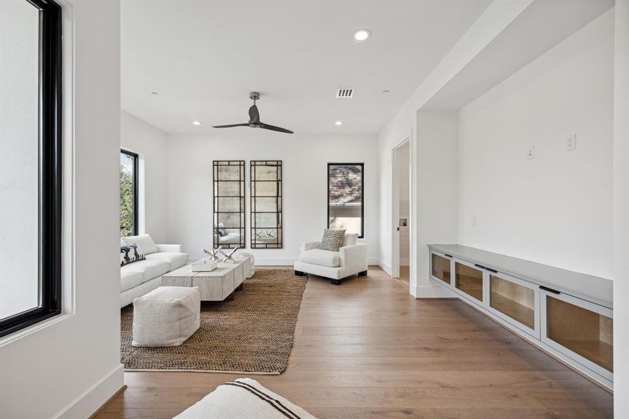 A built-in floating entertainment center with glass doors adds a touch of sophistication and provides ample storage space.