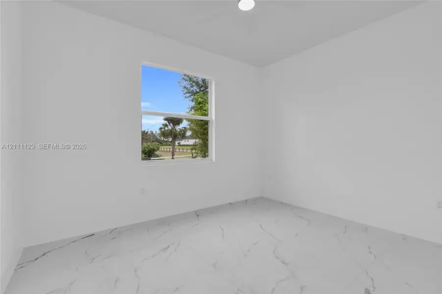 Bedroom with window and porcelain tile flooring.