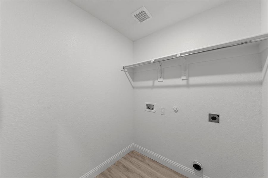 Laundry area with hookup for a gas dryer, light wood-style floors, hookup for an electric dryer, and hookup for a washing machine