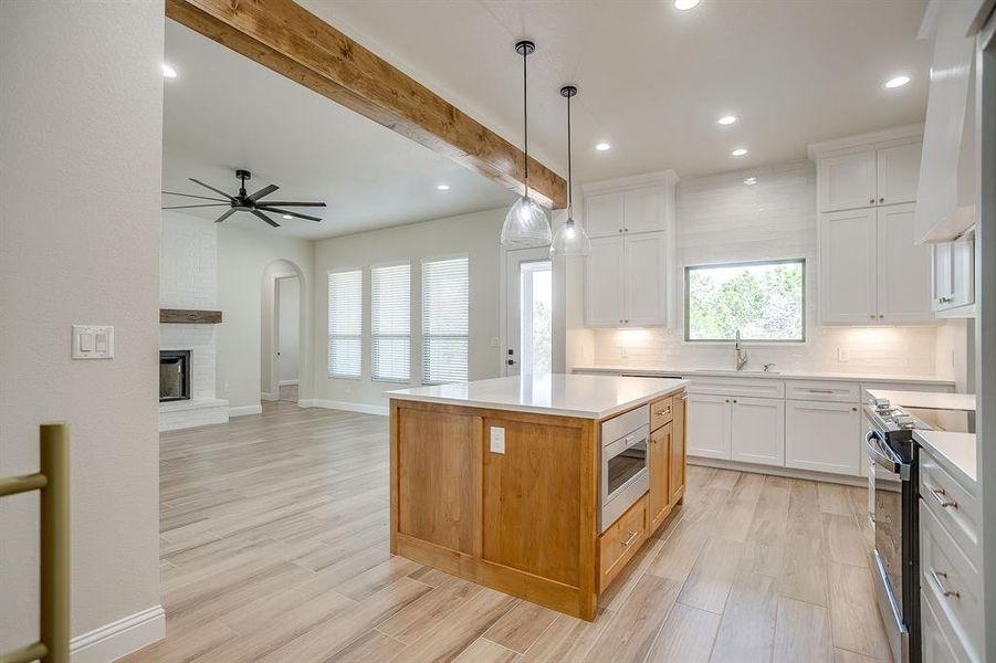 Kitchen featuring beam ceiling, stainless steel appliances, recessed lighting, light wood-style floors, and hanging light fixtures Kitchen featuring beam ceiling, stainless steel appliances, recessed lighting, light wood-style floors, and hanging light fixtures