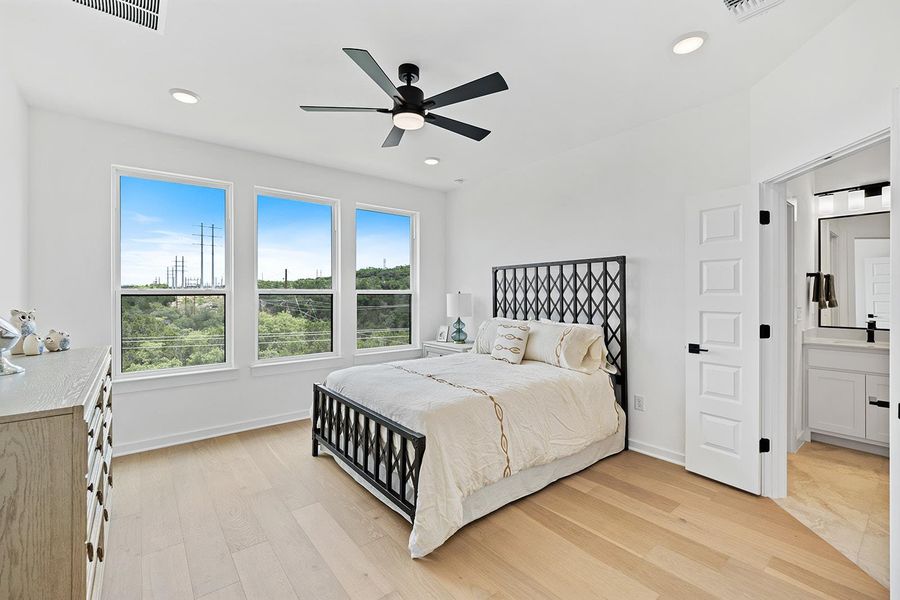 Large primary bedroom with views leads to ensuite spa inspired bathroom.