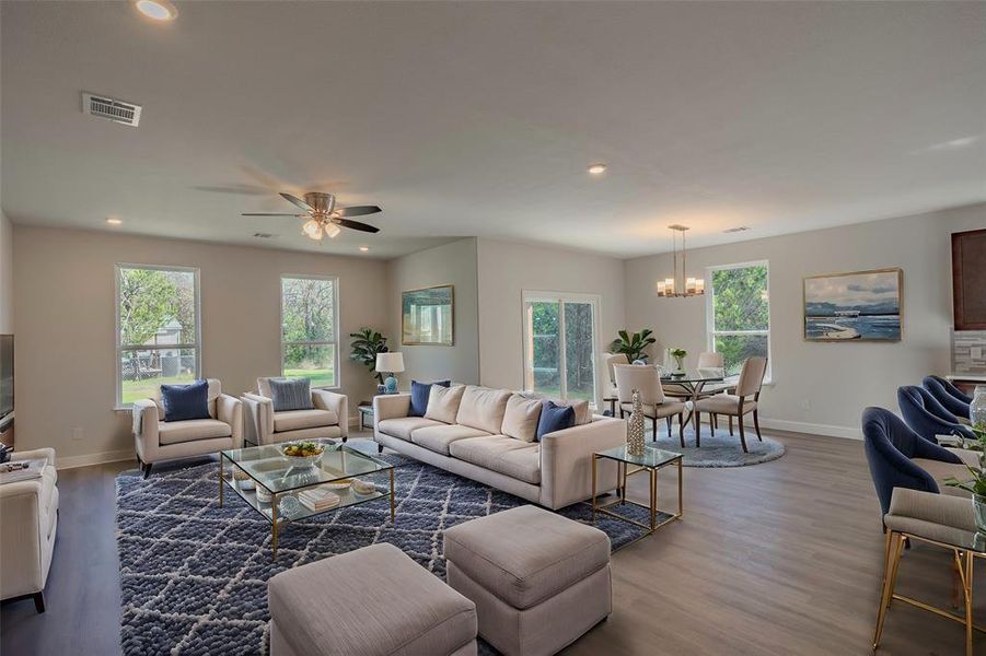 Living room with ceiling fan with notable chandelier and wood-type flooring