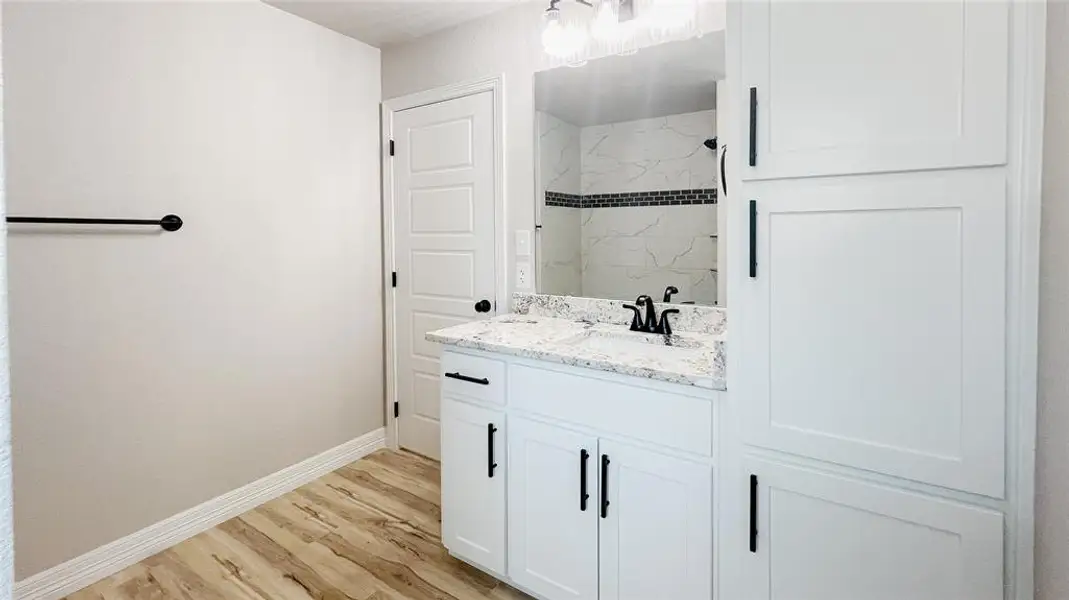 Bathroom with vanity, tiled shower, and wood finished floors Bathroom with vanity, tiled shower, and wood finished floors
