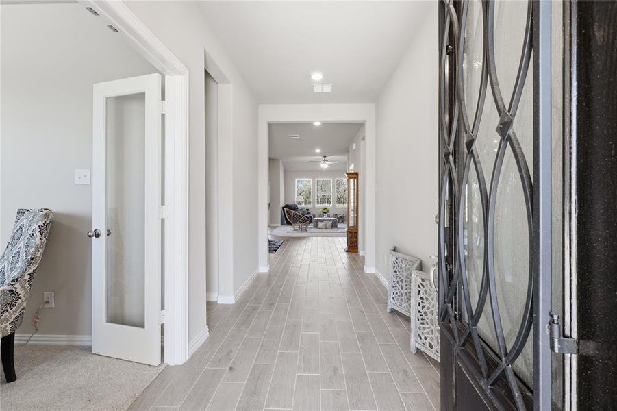 Entryway featuring a decorative iron and glass front door, light wood-finish flooring, recessed lighting, and a white interior door with frosted glass paneling