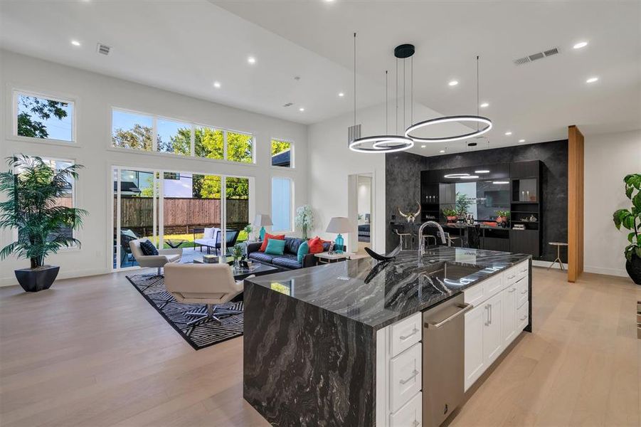 Kitchen with a sink, light wood-style floors, recessed lighting, and a towering ceiling