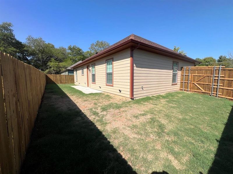 View of home's exterior featuring a fenced backyard, a patio area, and a shingled roof