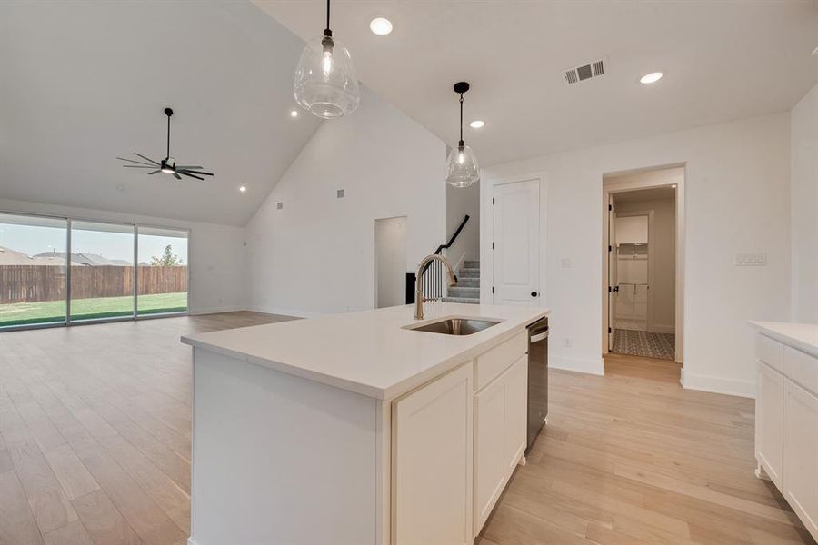 Kitchen featuring high vaulted ceiling, light wood-type flooring, white cabinetry, pendant lighting, and recessed lighting Kitchen featuring high vaulted ceiling, light wood-type flooring, white cabinetry, pendant lighting, and recessed lighting