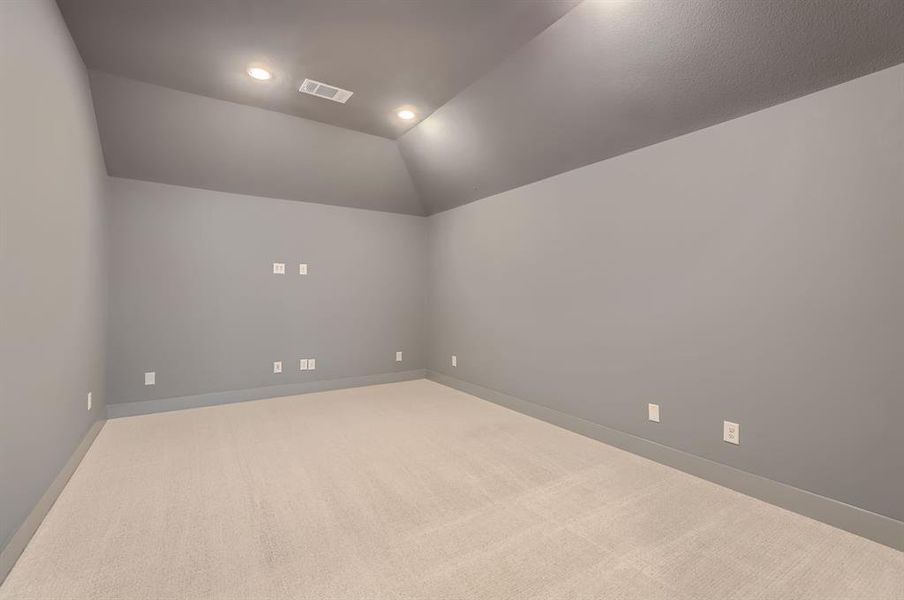 Carpeted empty room featuring vaulted ceiling