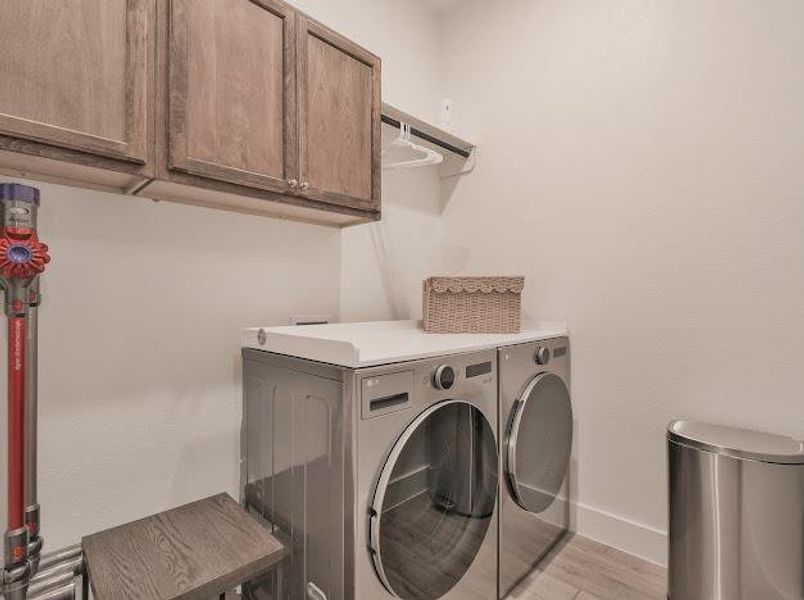 Washroom with light wood-style floors, cabinet space, and washer and dryer Washroom with light wood-style floors, cabinet space, and washer and dryer