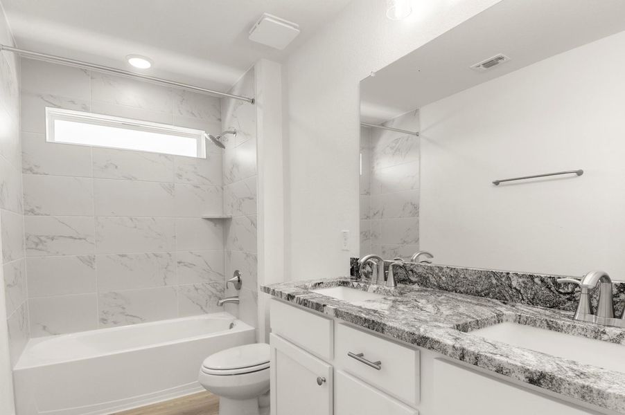 Full bath with double vanity, washtub / shower combination, and light wood finished floors Full bath with double vanity, washtub / shower combination, and light wood finished floors